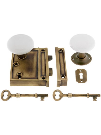 Solid Brass Vertical Rim Lock Set with White Porcelain Knobs in Antique Brass.